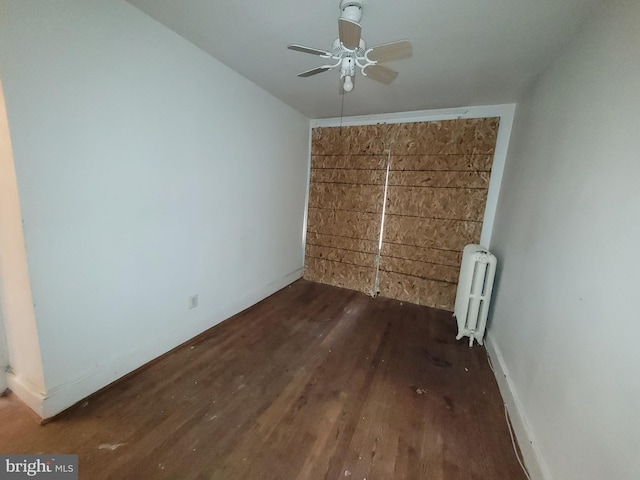 unfurnished bedroom featuring radiator heating unit, ceiling fan, and dark wood-type flooring