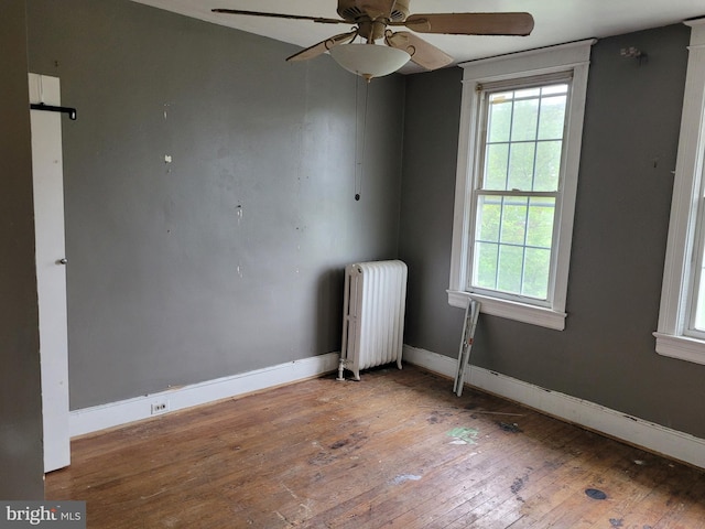 spare room featuring ceiling fan, radiator heating unit, and wood-type flooring