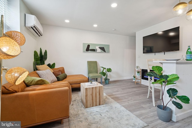 living room with a wall unit AC and light hardwood / wood-style floors