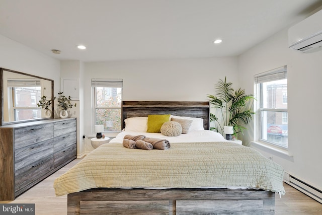 bedroom featuring a baseboard radiator, a wall unit AC, and light hardwood / wood-style floors