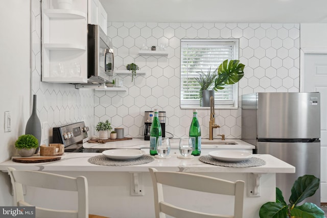 interior space featuring white cabinets, kitchen peninsula, a breakfast bar area, and stainless steel appliances