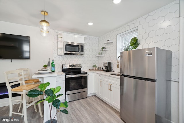 kitchen featuring white cabinets, tasteful backsplash, light wood-type flooring, and stainless steel appliances