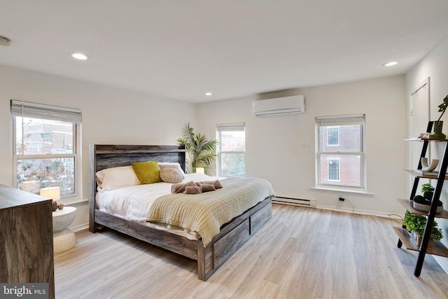 bedroom with multiple windows, light hardwood / wood-style flooring, and a wall mounted air conditioner