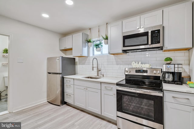 kitchen featuring light hardwood / wood-style floors, stainless steel appliances, white cabinetry, and sink