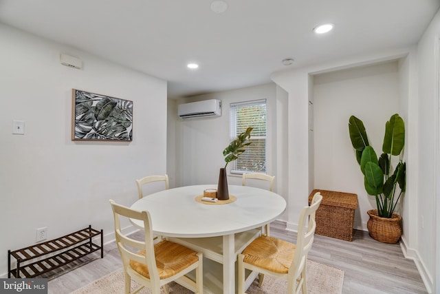 dining area with a wall mounted AC and light wood-type flooring