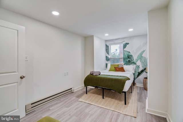 bedroom featuring light wood-type flooring and a baseboard heating unit