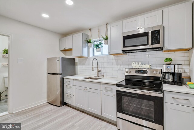 kitchen featuring white cabinets, appliances with stainless steel finishes, light hardwood / wood-style floors, and sink