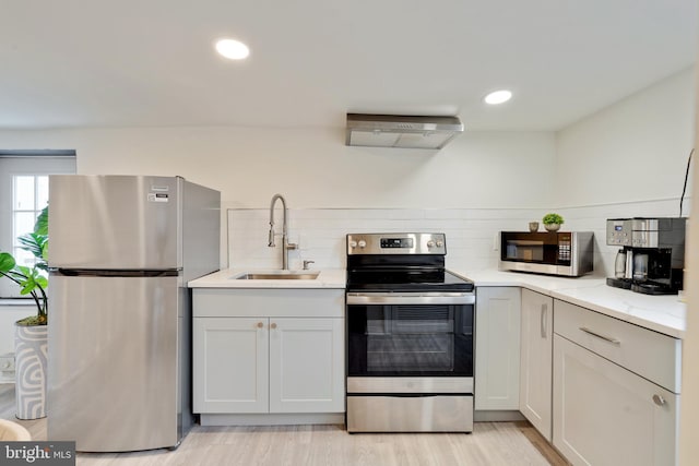 kitchen with tasteful backsplash, light wood-type flooring, appliances with stainless steel finishes, and sink