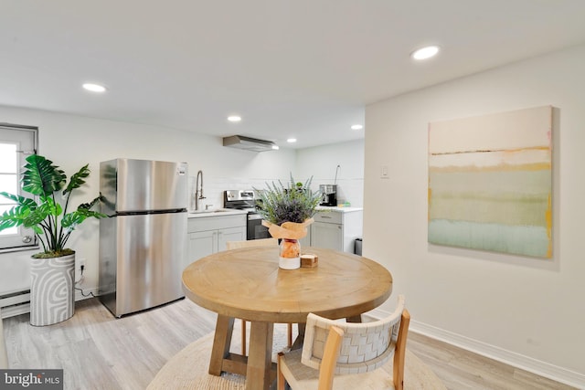 dining room featuring light hardwood / wood-style flooring, baseboard heating, and sink