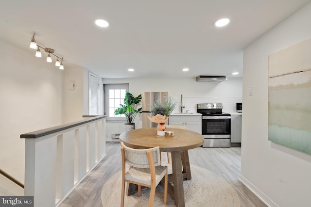 dining room with light hardwood / wood-style flooring, sink, rail lighting, and a wall mounted AC