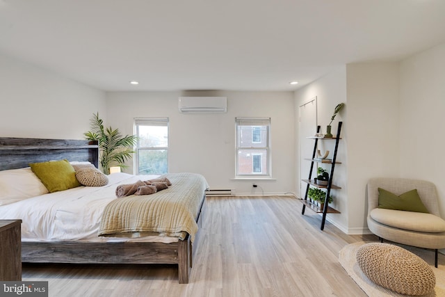 bedroom featuring a wall mounted AC, light hardwood / wood-style floors, and a baseboard heating unit