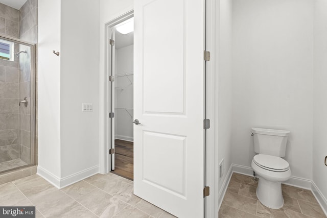 bathroom featuring toilet and a shower with shower door