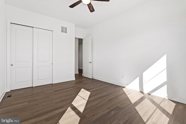 unfurnished bedroom with a closet, ceiling fan, and dark wood-type flooring