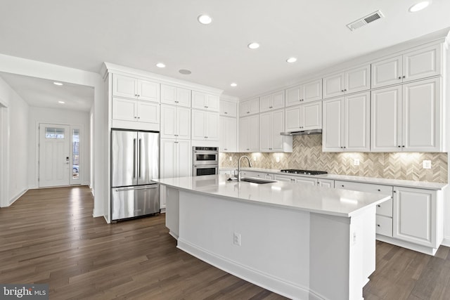 kitchen featuring stainless steel appliances, sink, a center island with sink, white cabinets, and dark hardwood / wood-style floors