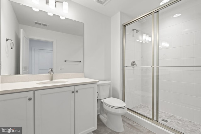 bathroom featuring tile patterned floors, vanity, an enclosed shower, and toilet