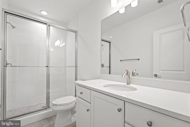 bathroom featuring vanity, toilet, and a shower with door