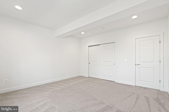 unfurnished bedroom with carpet and beamed ceiling