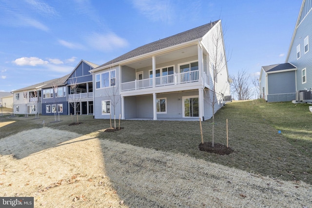 view of front of property featuring a balcony, central AC unit, and a front yard