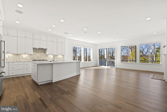 kitchen with dark hardwood / wood-style flooring, white cabinetry, plenty of natural light, and an island with sink