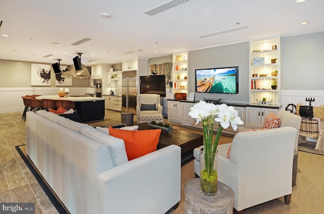 living room with built in shelves and light hardwood / wood-style floors