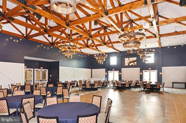 dining room featuring beam ceiling, a towering ceiling, and a chandelier