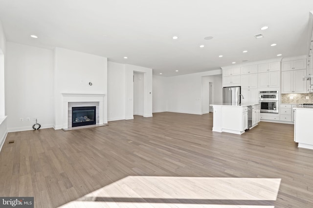 unfurnished living room with light hardwood / wood-style flooring and sink