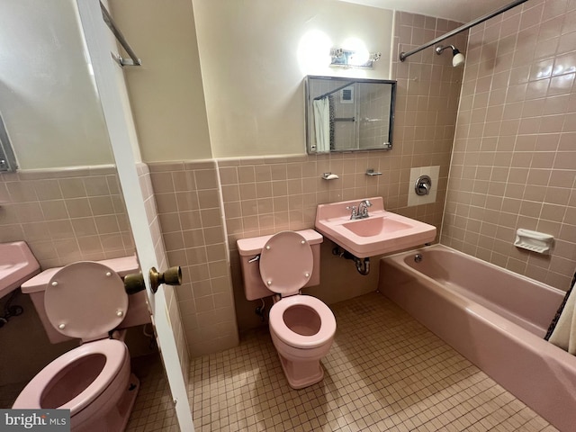 full bathroom with tiled shower / bath combo, sink, tile walls, tile patterned flooring, and toilet