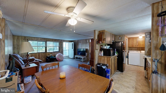 dining room featuring separate washer and dryer, wood walls, and ceiling fan