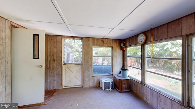 unfurnished sunroom featuring a healthy amount of sunlight and an AC wall unit