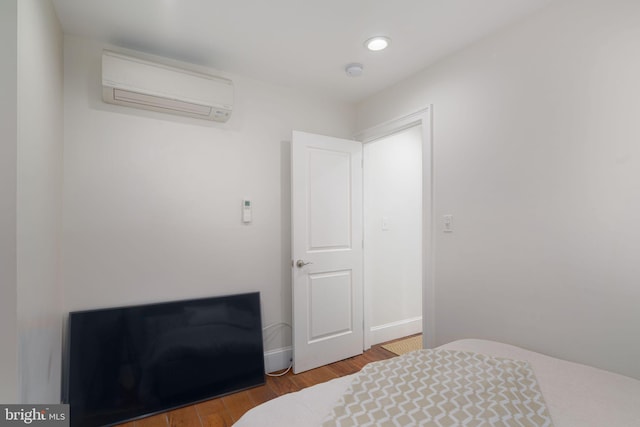 bedroom with dark hardwood / wood-style flooring and an AC wall unit