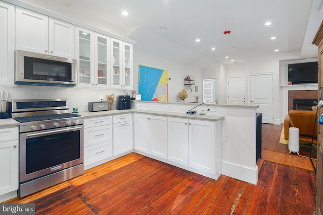 kitchen with kitchen peninsula, white cabinetry, dark hardwood / wood-style flooring, and stainless steel appliances