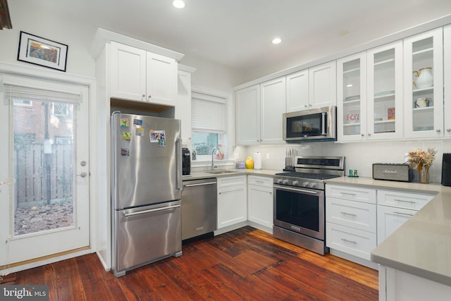 kitchen with sink, white cabinets, stainless steel appliances, dark wood-type flooring, and tasteful backsplash