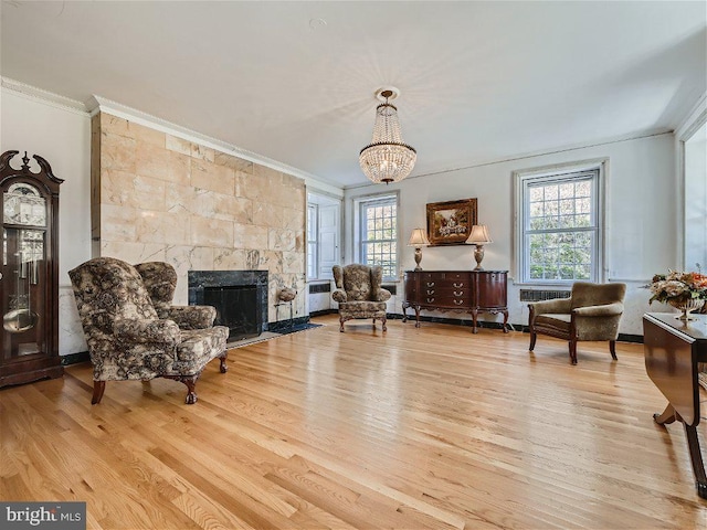 living area featuring an inviting chandelier, light hardwood / wood-style flooring, a fireplace, and plenty of natural light