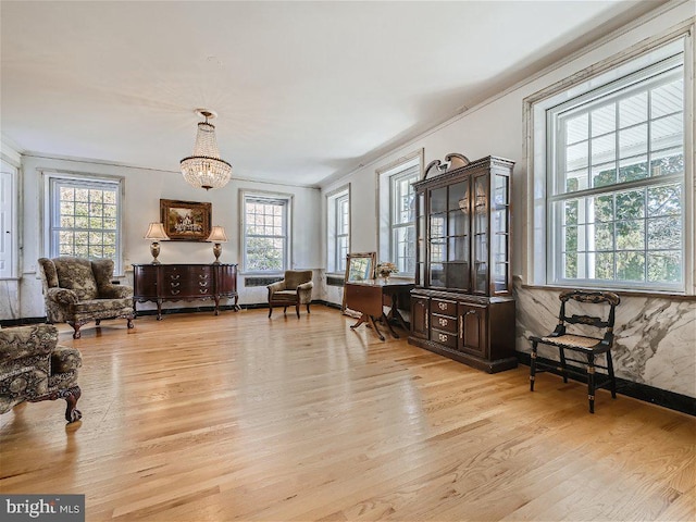 living area with a chandelier, light hardwood / wood-style floors, and crown molding