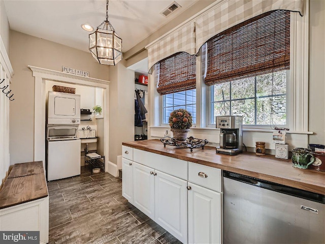 kitchen featuring stacked washer and dryer, decorative light fixtures, stainless steel dishwasher, a notable chandelier, and butcher block countertops