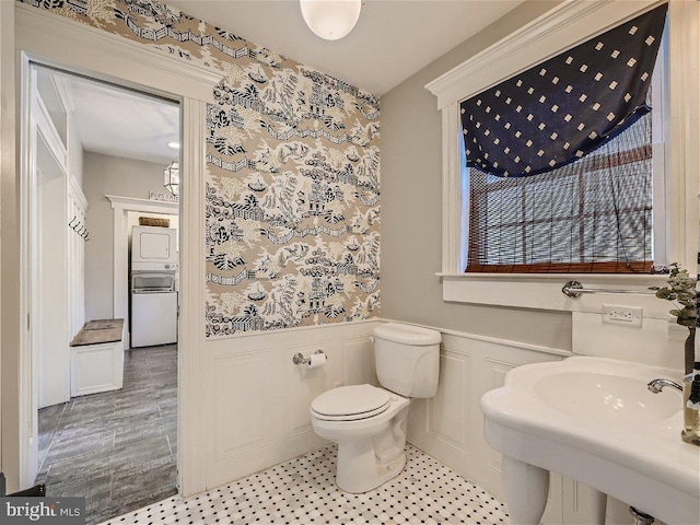 bathroom featuring tile flooring, toilet, and stacked washer and dryer