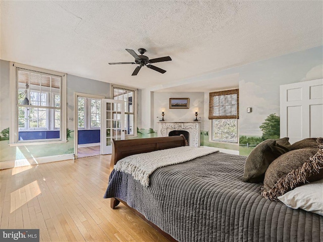 bedroom with a textured ceiling, light hardwood / wood-style floors, and ceiling fan