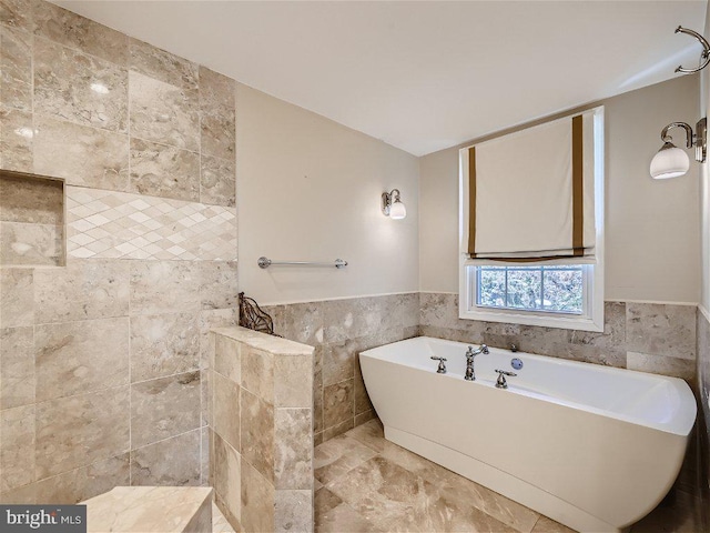 bathroom with a bath to relax in, tile flooring, and tile walls