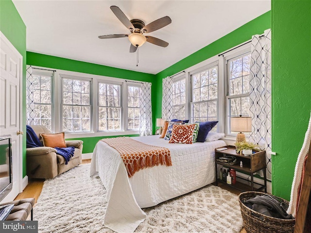 bedroom with light wood-type flooring, ceiling fan, and multiple windows