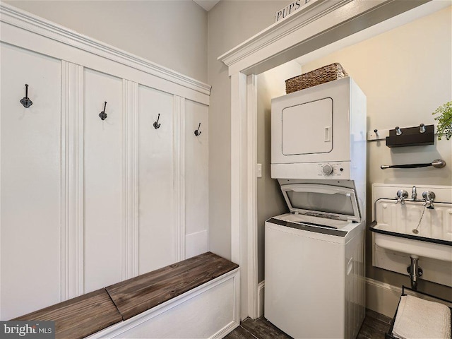 laundry room featuring dark wood-type flooring and stacked washer and dryer