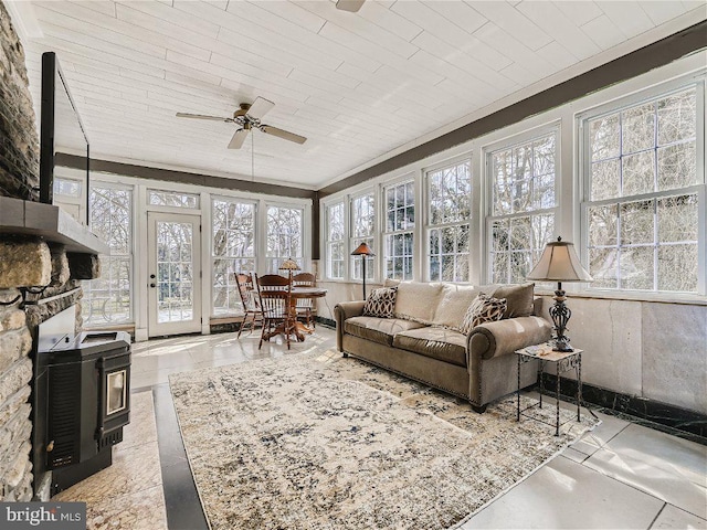 sunroom featuring ceiling fan, a wood stove, and a fireplace