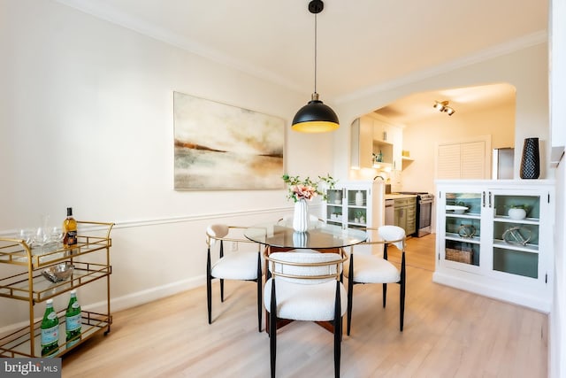 dining area with light wood-type flooring and ornamental molding