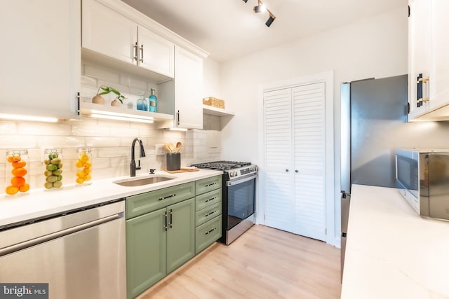 kitchen featuring white cabinetry, green cabinets, appliances with stainless steel finishes, decorative backsplash, and sink