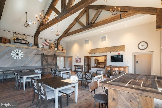 dining room with an inviting chandelier, beam ceiling, high vaulted ceiling, dark hardwood / wood-style flooring, and a barn door