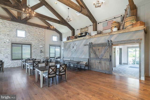 dining room featuring a barn door, a chandelier, and high vaulted ceiling