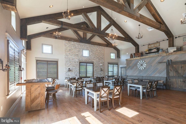 dining space featuring an inviting chandelier, high vaulted ceiling, and a barn door