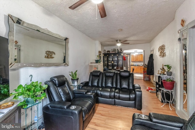 living room featuring ceiling fan, a textured ceiling, and light hardwood / wood-style floors