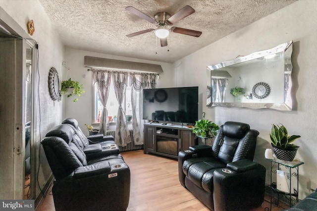 living room featuring ceiling fan, a textured ceiling, and light hardwood / wood-style floors