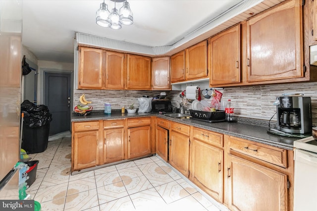 kitchen featuring tasteful backsplash, light tile floors, sink, and an inviting chandelier