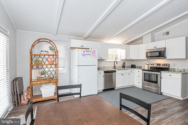 kitchen with white cabinetry, appliances with stainless steel finishes, and vaulted ceiling with beams